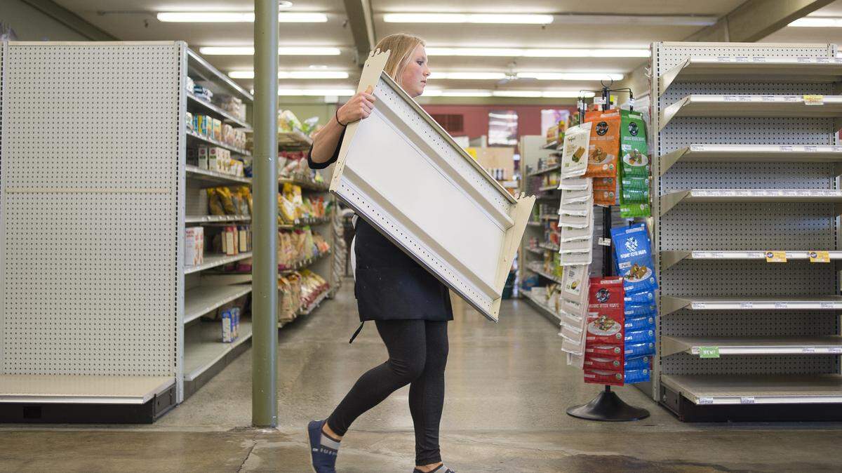 Brittany Beug, Terra Organic and Natural Foods employee, carries a detached shelf while consolidating items from aisle end caps on Friday, May 11, in Bellingham. 