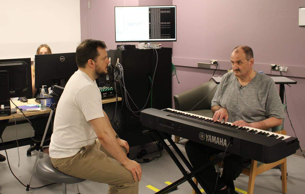 Keith McKenzie, right, and Adria Robert-Gonzalez work on McKenzie’s rehabilitation exercises May 17 at UW Medicine in Seattle. McKenzie suffered a stroke in 2021 and is participating in a clinic trial that involves using an implanted device to stimulate the brain and help regain function.