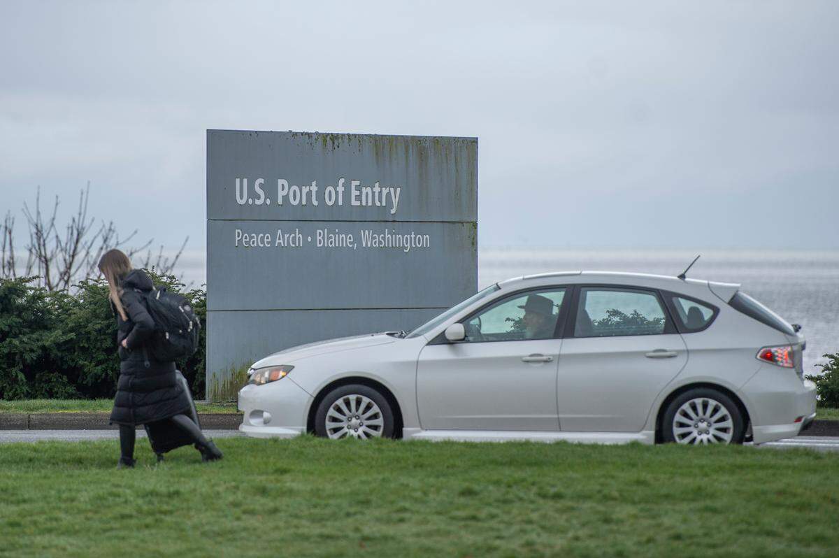 People cross the border between the U.S. and Canada at Peace Arch Park on March 18 in Blaine. On Friday, Canada will drop its requirement for testing of vaccinated travelers.