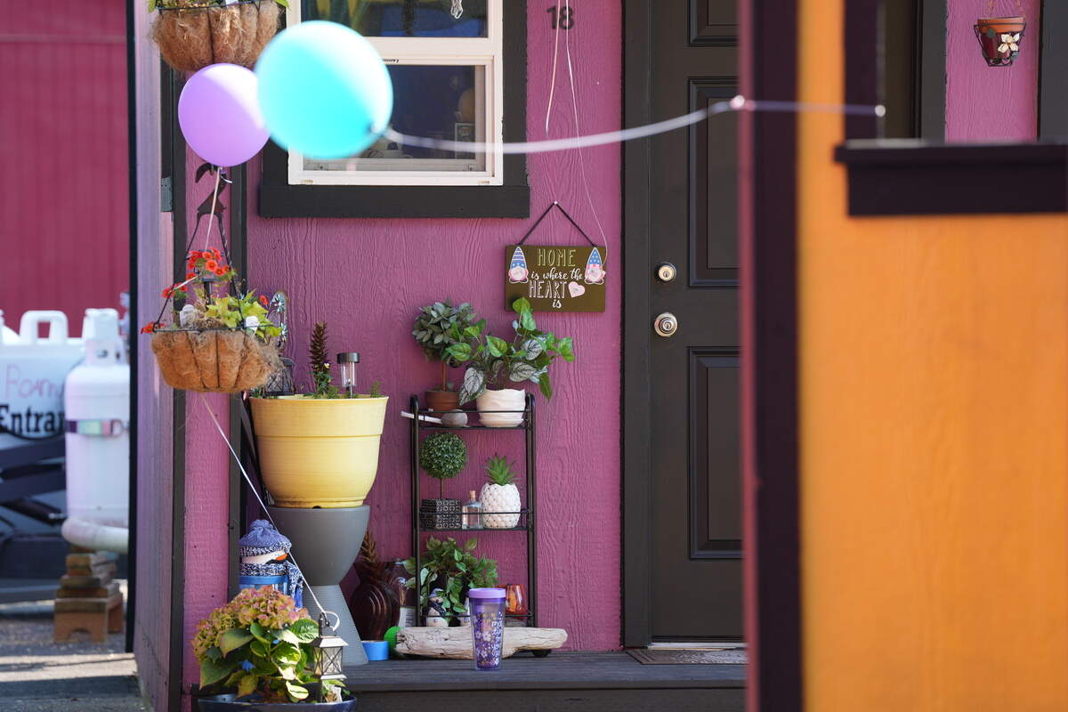 A tiny home in the North Haven village is decorated with plants and a sign.
