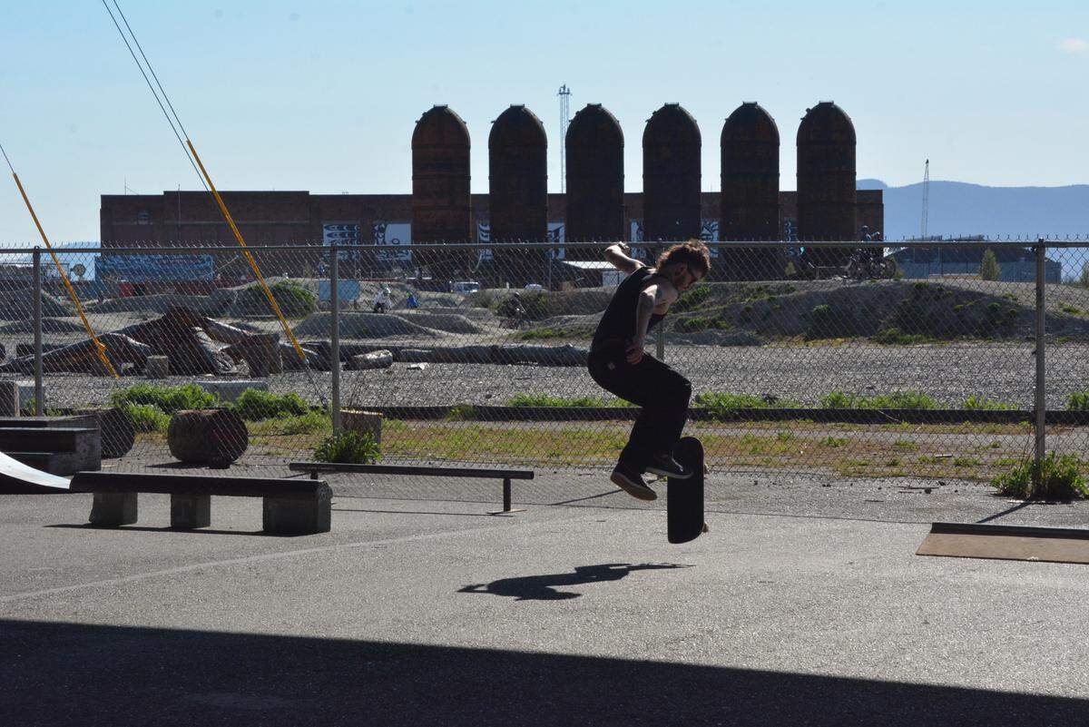 A skateboarder performs a trick at a makeshift skatepark under the Roeder Avenue bridge on Wednesday, April 16, 2025, in Bellingham, Wash. In the background are the iconic “rocket ships,” part of the former Georgia-Pacific paper mill that once occupied the site.