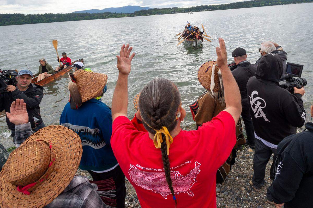 Lummi Nation elder Phreddie Xwenang Lane, center, prays for safe travels as a canoe leaves the Gathering of the Eagles canoe landing celebration at the Lummi Stommish grounds on Friday afternoon May 27, on the Lummi Reservation in Whatcom County.