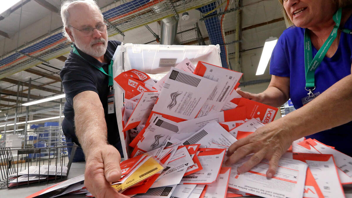 Election workers Mark Bezanson, left, and Julie Olson dump ballots collected earlier in the day from drop boxes onto a table for sorting at the King County Elections office, Monday, Nov. 5, 2018, in Renton, Wash.