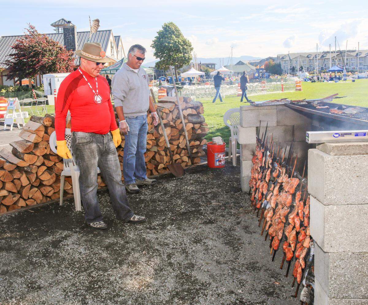 Willie Lane, left, and Dana Wilson oversee the Lummi Nation open-pit grilled salmon at SeaFeed at the Harbor during the Bellingham SeaFeast. The dining pavilion in Squalicum Harbor will be open Sept. 21-22 lunch through dinner this year.