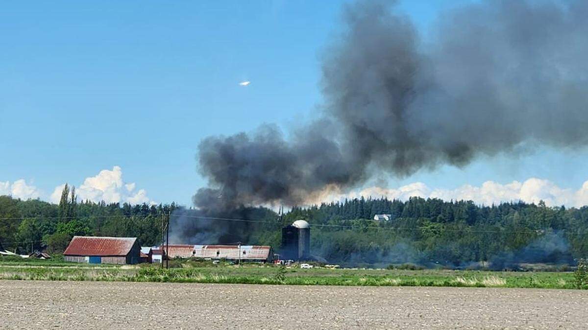 A barn full of hay and farm equipment burns near the corner of Lampman and Church roads west of Ferndale, Wash., on Wednesday, May 10, 2023.