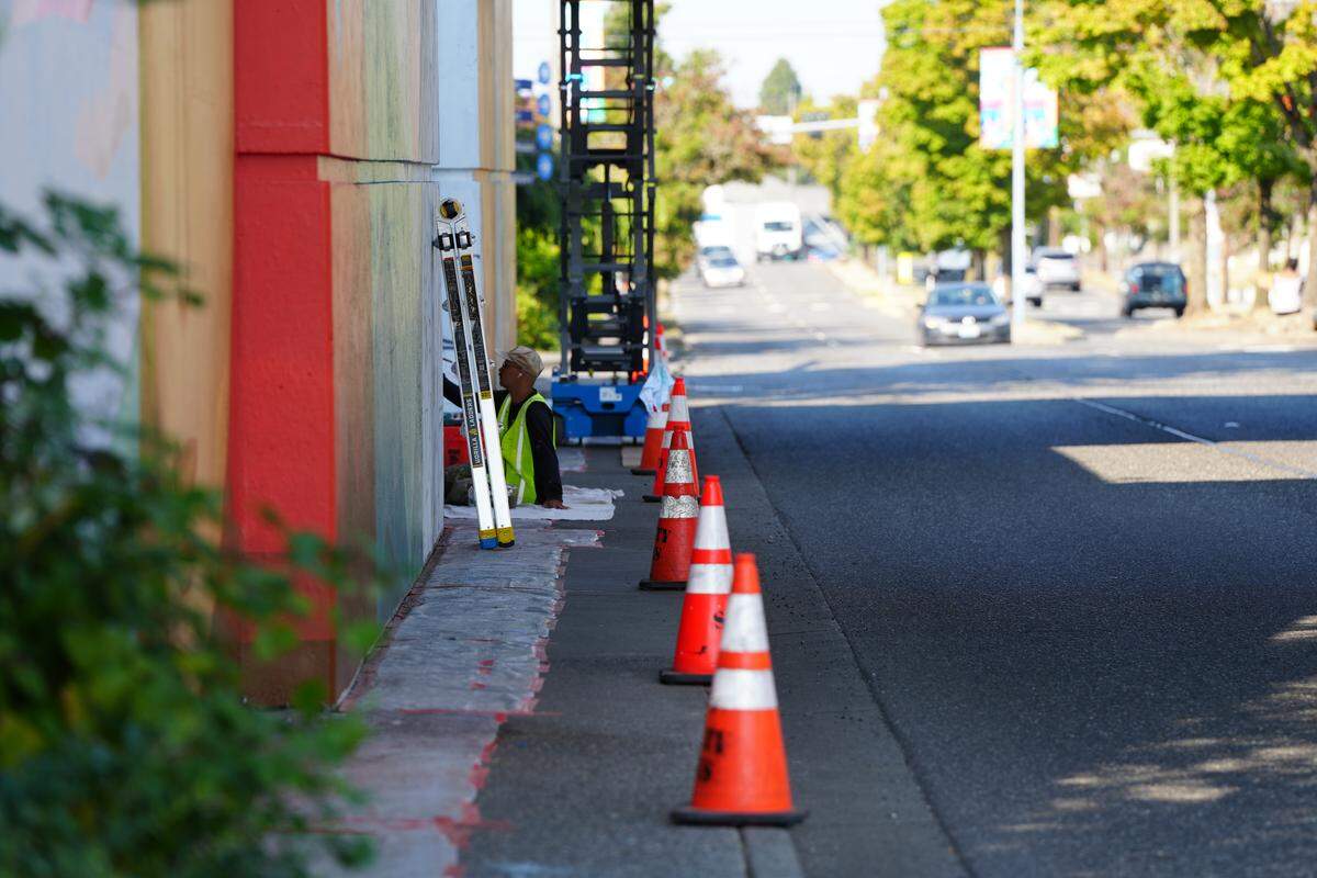 Denver-based street artist Pedro Barrios works on his new mural behind a line of safety cones.