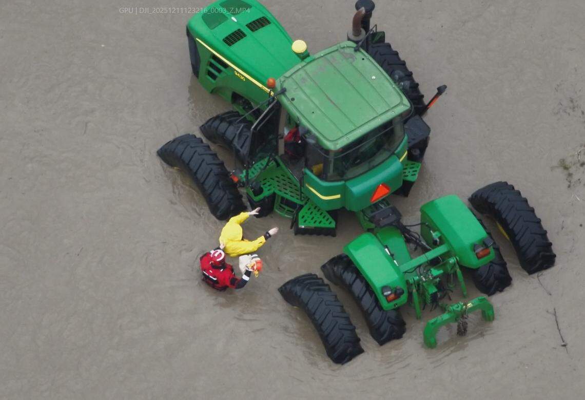 Rescuers escort a Sumas woman to a tractor that was donated to rescue teams during the flooding of December 2025. The woman was rescued by a police officer with water-rescue training who helped the woman from her home, which was submerged in about 6 feet of water.