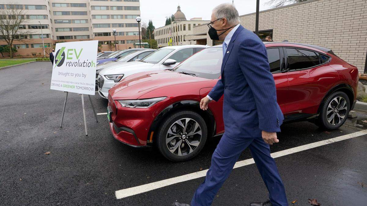 Washington Gov. Jay Inslee walks past a Ford Mustang Mach-E electric vehicle, Monday, Dec. 13, 2021, following a news conference in Olympia, Wash. Inslee announced several climate-related proposals for the 2022 legislative session, including a plan to offer rebates on the purchase of new and used electric vehicles for qualified buyers.