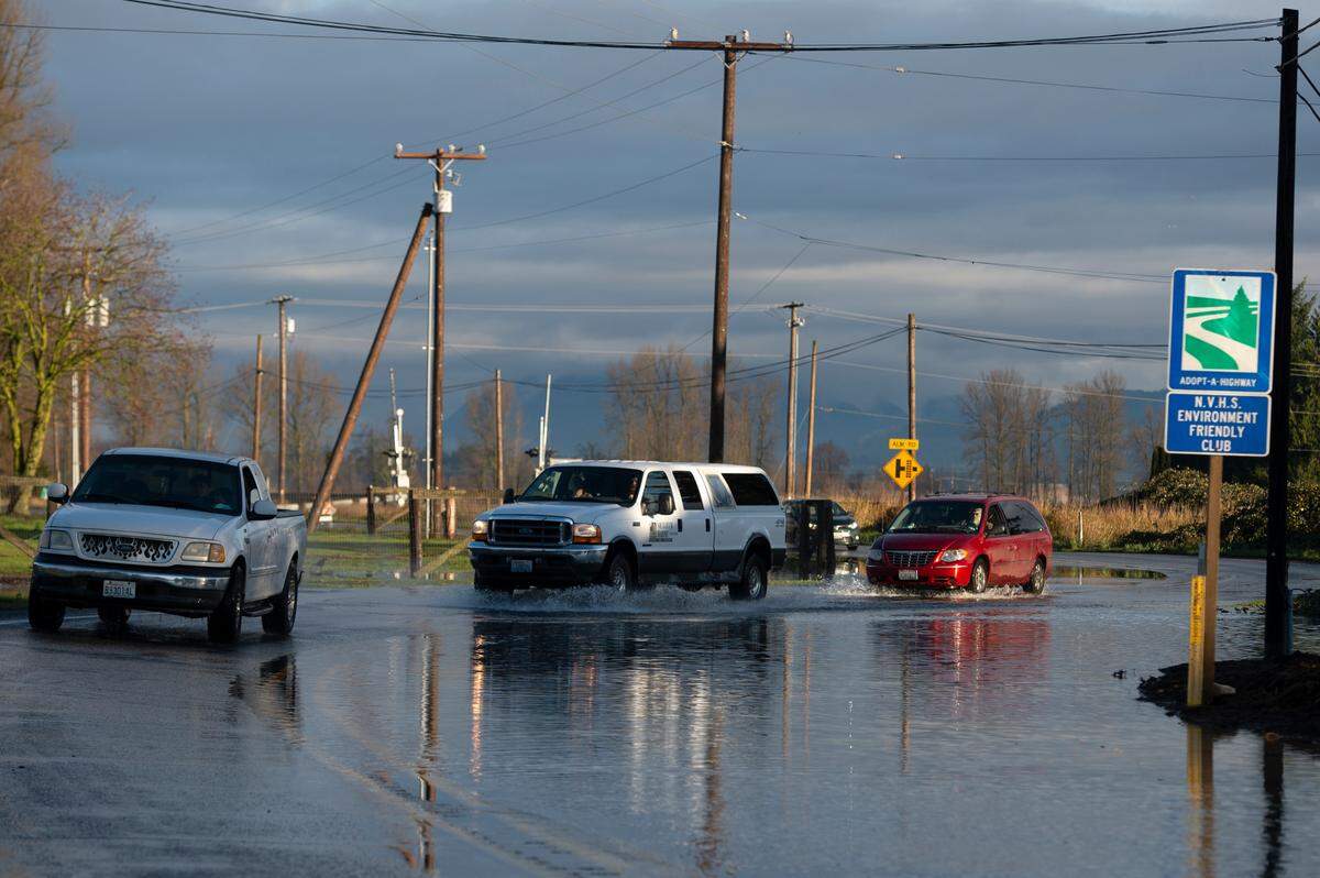 Cars pass over Highway 9 near Alm Road during flooding on Monday, Nov. 29, 2021, in Everson, Wash.