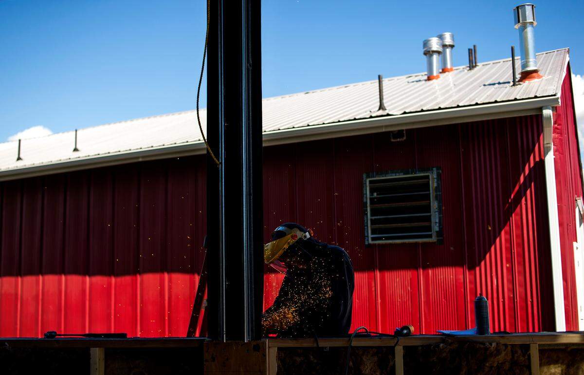 Luis Zamudio, a Custom Design, Inc. employee, grinds down welds around the edge of a garage door style window of the future restaurant at Twin Sisters Brewing on Monday in Bellingham. The red building behind Zamudio is the brewery.