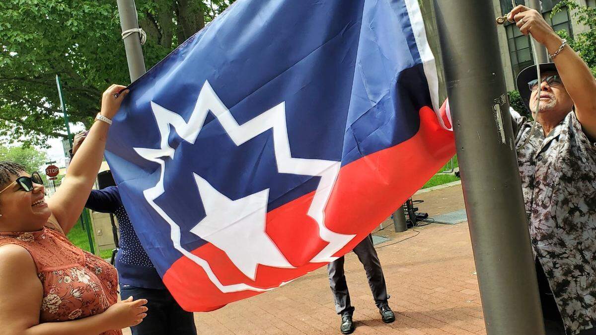 City Council members Kristina Michele Martens, left, and Edwin “Skip” Williams” hoist the Juneteenth flag together on June 17 in front of City Hall in Bellingham.