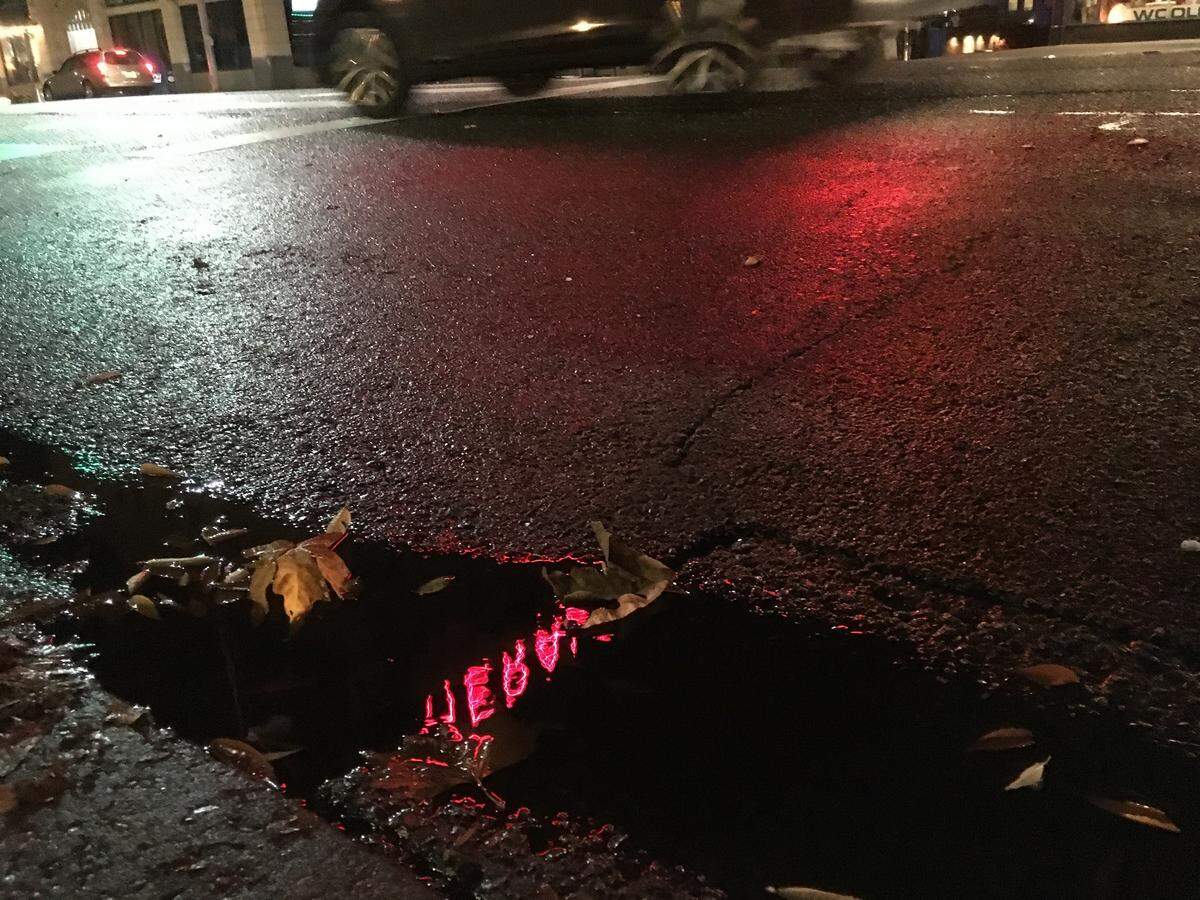 The Herald Building sign is reflected in a puddle after light rain Wednesday morning in downtown Bellingham.