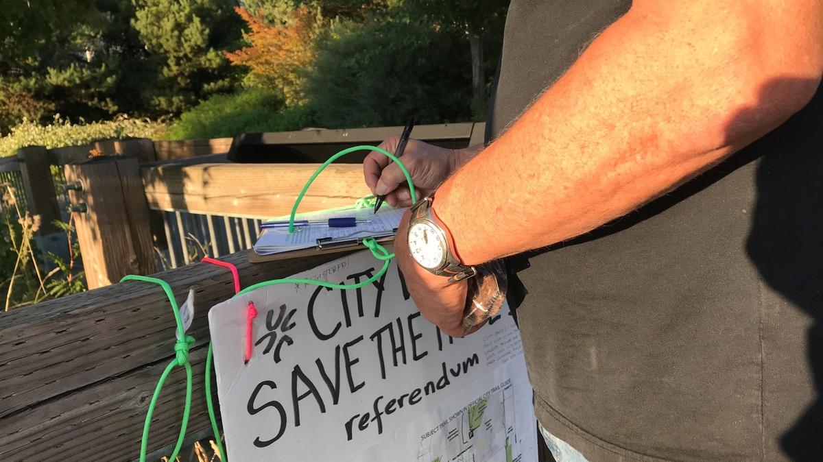 A person signs a petition for the Save the Trails referendum on Tuesday, Sept. 7, at Taylor Dock in Bellingham.