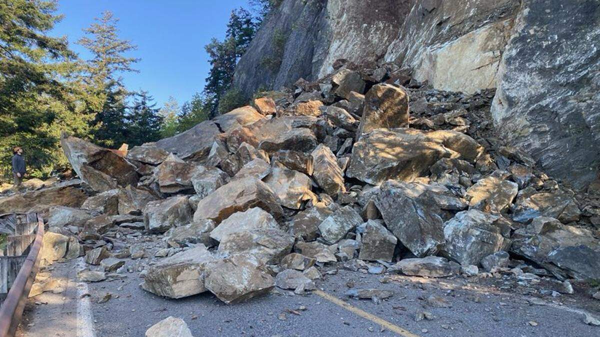 A person (left) looks up at a rockslide covering all lanes on Chuckanut Drive just north of Blanchard Road.
