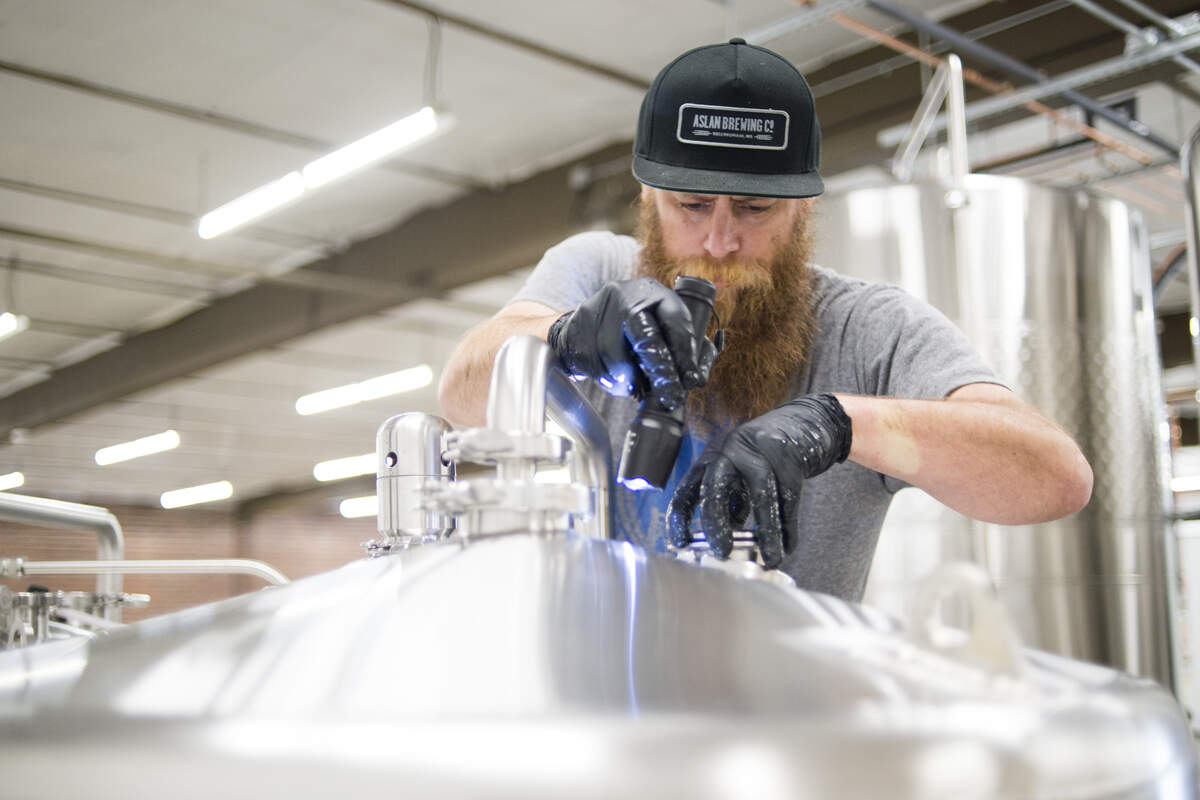 Abraham Ebert, co-owner of Lost Giants Cider Company, looks in a tank while making cider Tuesday at the Bellingham business in the Haskell Business Park.