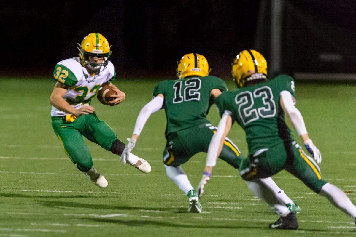 Lynden running back Lane Heeringa (32) attempts to evade Sehome defenders Braddock Duckworth (12) and Alden Jacobs (23) as he sweeps around the defensive line during the third quarter on Friday evening Oct. 15, 2021, at Civic Field in Bellingham, Wash. The Lynden Lions defeated the Sehome Mariners 23 to 7.
