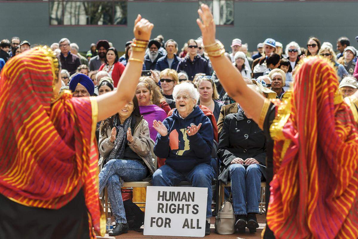 Phyllis Kiehn of Bellingham claps as the Rhythm of India dancers entertain the crowd at the dedication ceremony for the Arch Of Healing and Reconciliation at Bellingham City Hall on Saturday in Bellingham.