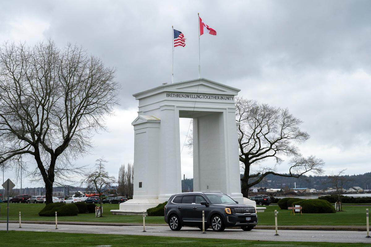 People cross the border between the U.S. and Canada at Peace Arch Park on Friday, March 18, 2022, in Blaine, Wash.