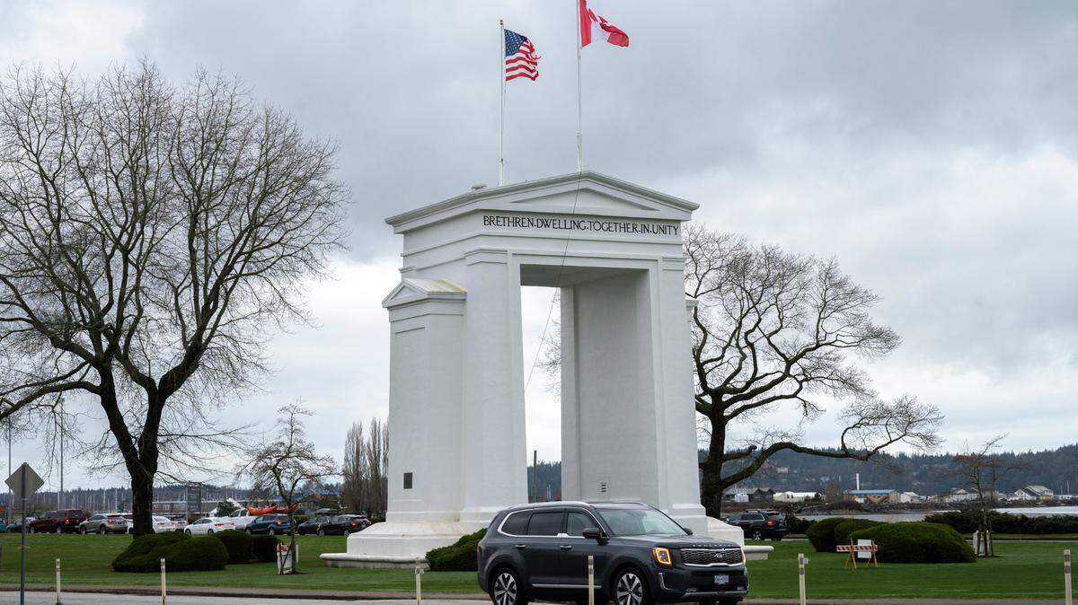 People cross the border between the U.S. and Canada at Peace Arch Park on Friday, March 18, 2022, in Blaine, Wash.