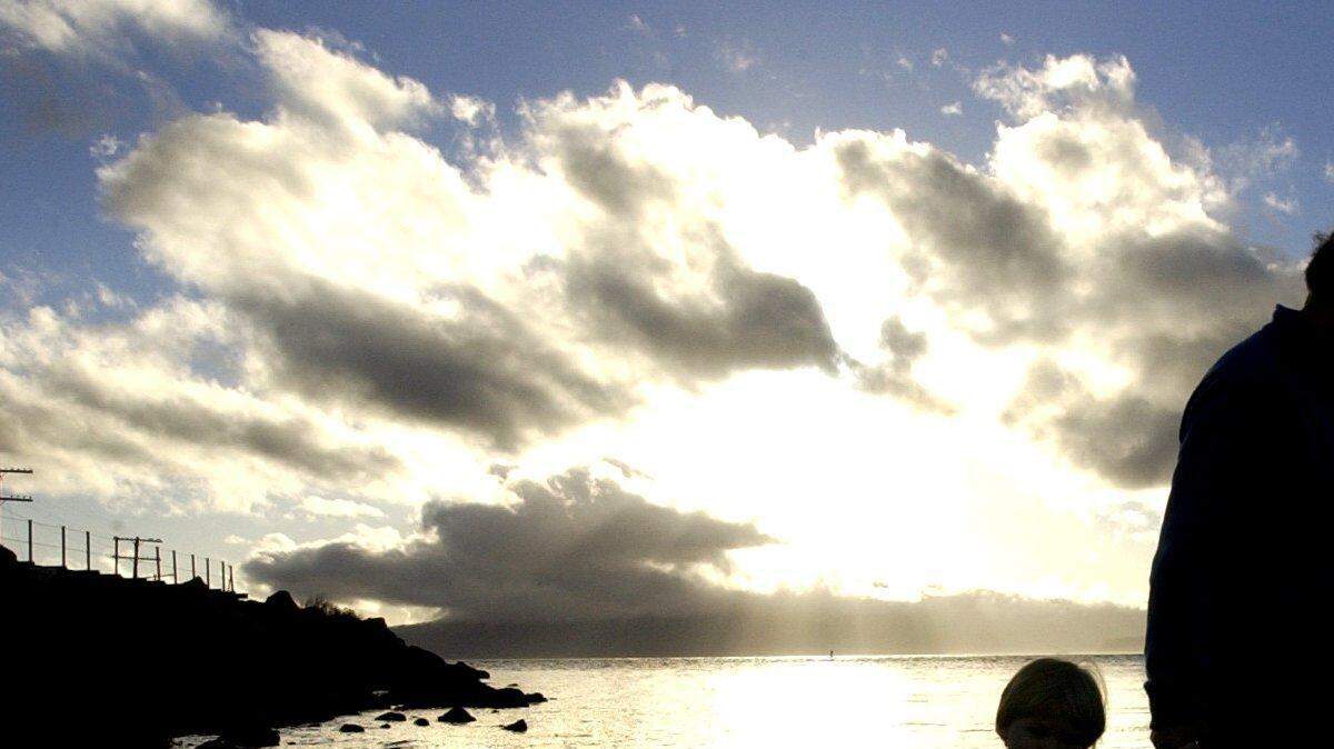 As the late afternoon sun sinks into the western clouds, David Flanagan of Bellingham walks the beach with his son, Ethan, 2 1/2, in this 2002 photo at Marine Park.