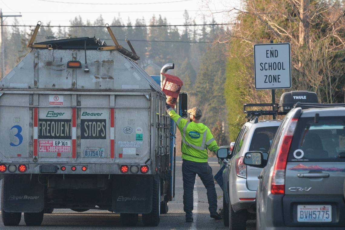 A Sanitary Services Co. worker lifts a recycling bin into a collection truck on Thursday, March 30, 2023, in the South Hill neighborhood of Bellingham, Wash. 