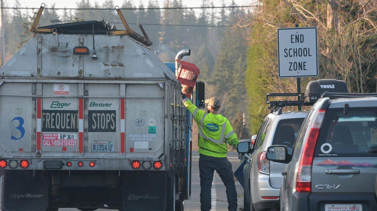 A Sanitary Services Co. worker lifts a recycling bin into a collection truck on Thursday, March 30, 2023, in the South Hill neighborhood of Bellingham, Wash.