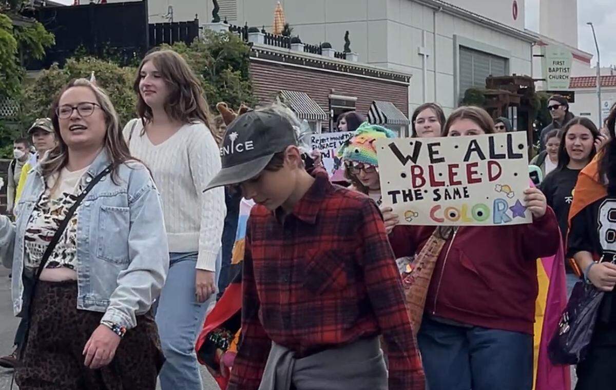 Participants in the Whatcom Youth Pride parade march part the historic Mount Baker Theatre in downtown Bellingham on Saturday.