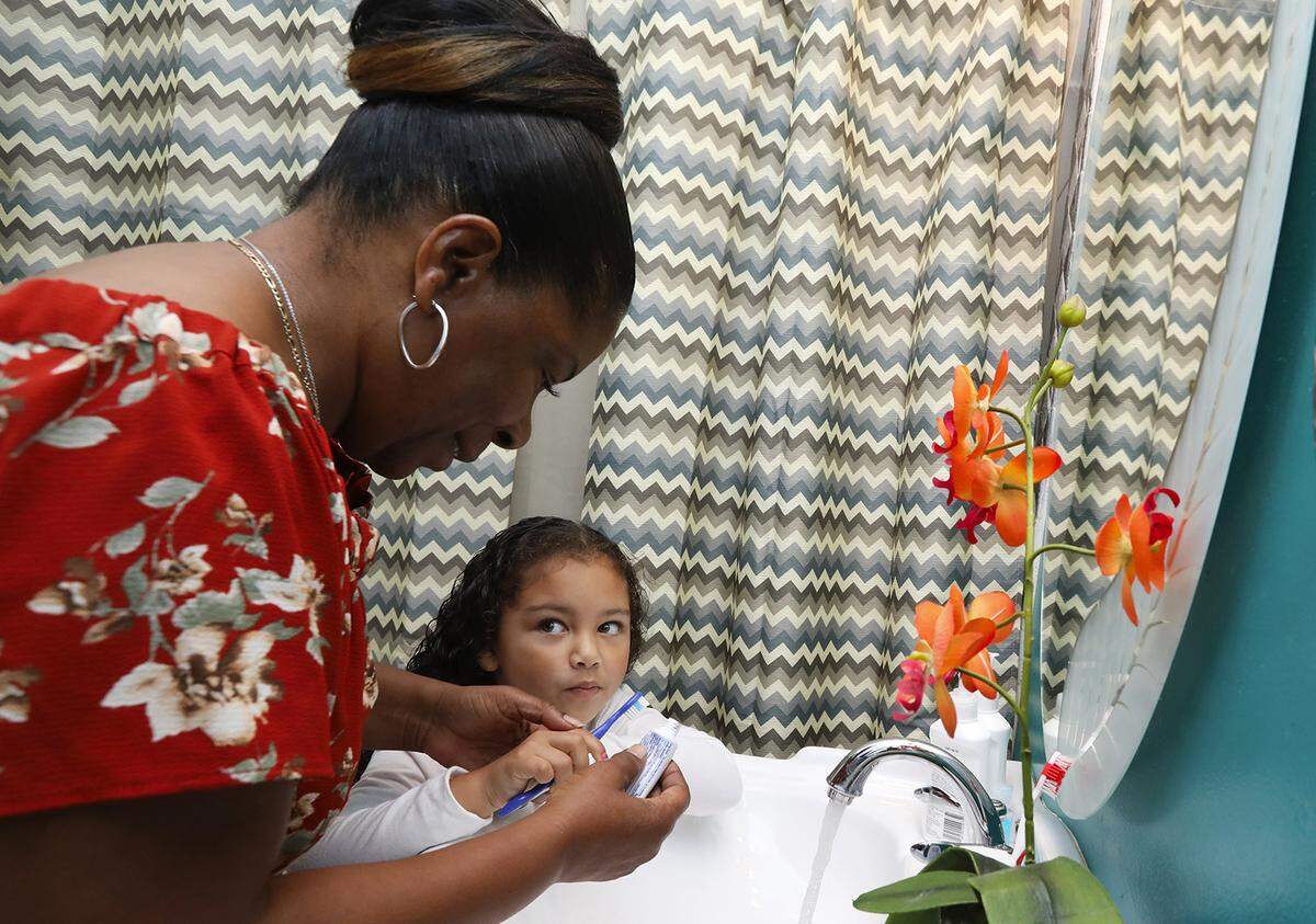 Alesia Cannady helps her 4-year-old granddaughter Aleiyah Cannady brush her teeth before taking her to preschool in September 2018 in Seattle. Alesia, 64, has raised Aleiyah almost from birth and doesn’t get benefits afforded to foster parents.