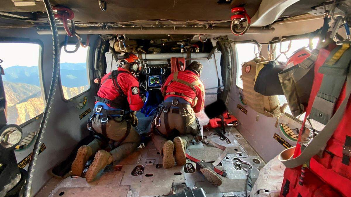 Members of a Whidbey Island Naval Air Station helicopter crew treat an injured speed-flyer who was rescued on Church Mountain on July3, 2023, east of Bellingham, Wash.