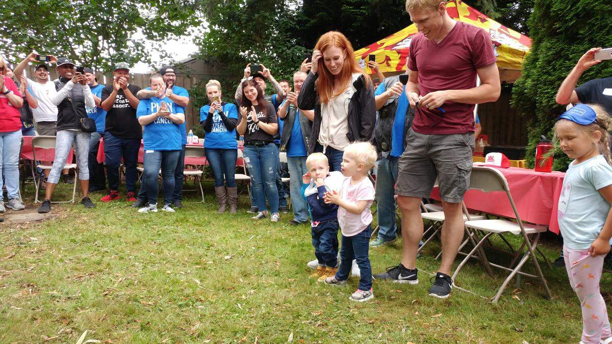 Eliza, 4, and Oliver, 2, Swanson, with their parents Kara and Seth, during the surprise revealing of a new playground in their backyard in Bellingham on Aug. 9.