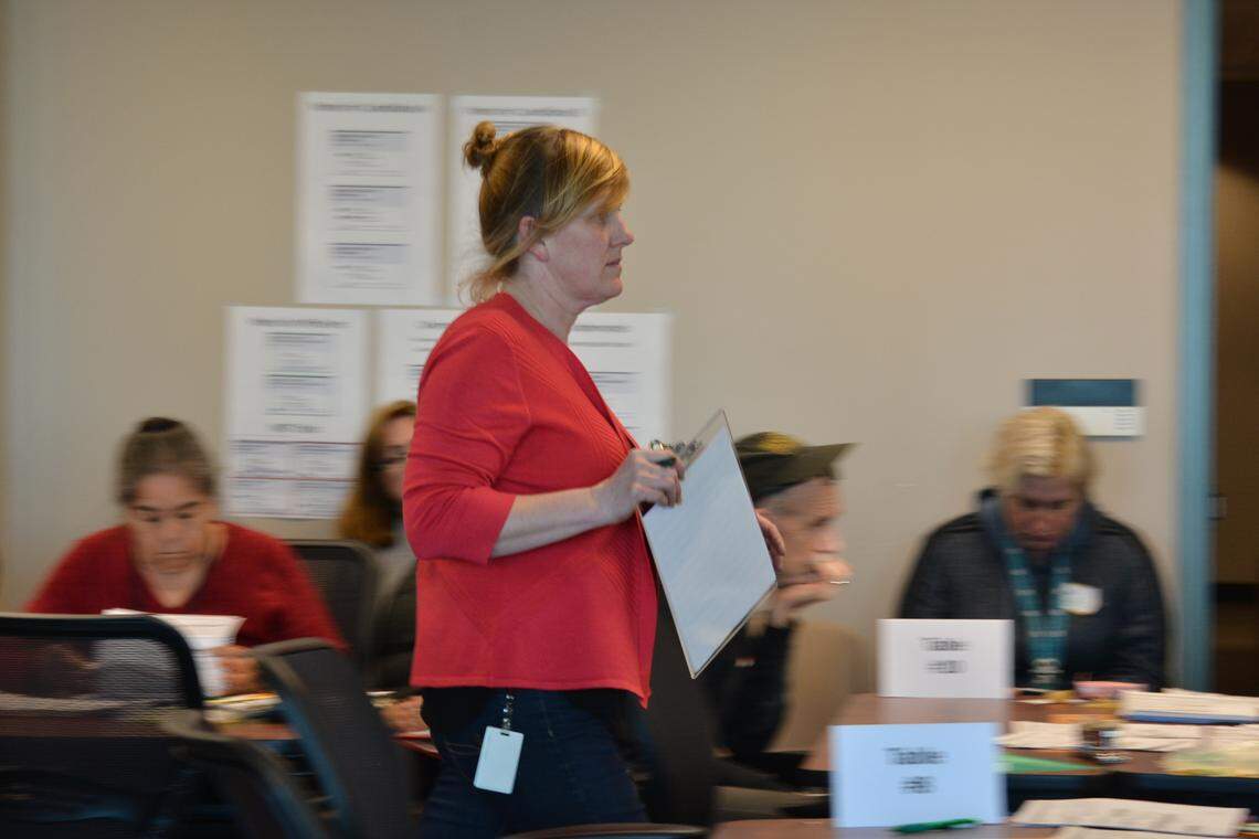 Elections Supervisor Amy Grasher walks past teams of workers Monday as the recount progressed Monday at the County Courthouse.