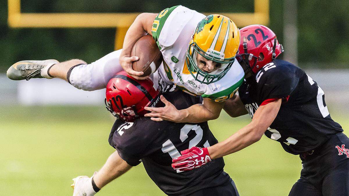 Lynden running back Steven DiLorenzo tries to leap over Mount Baker defenders Kaleb Bass (12) and Mark Tikhonov (22) Aug. 31.