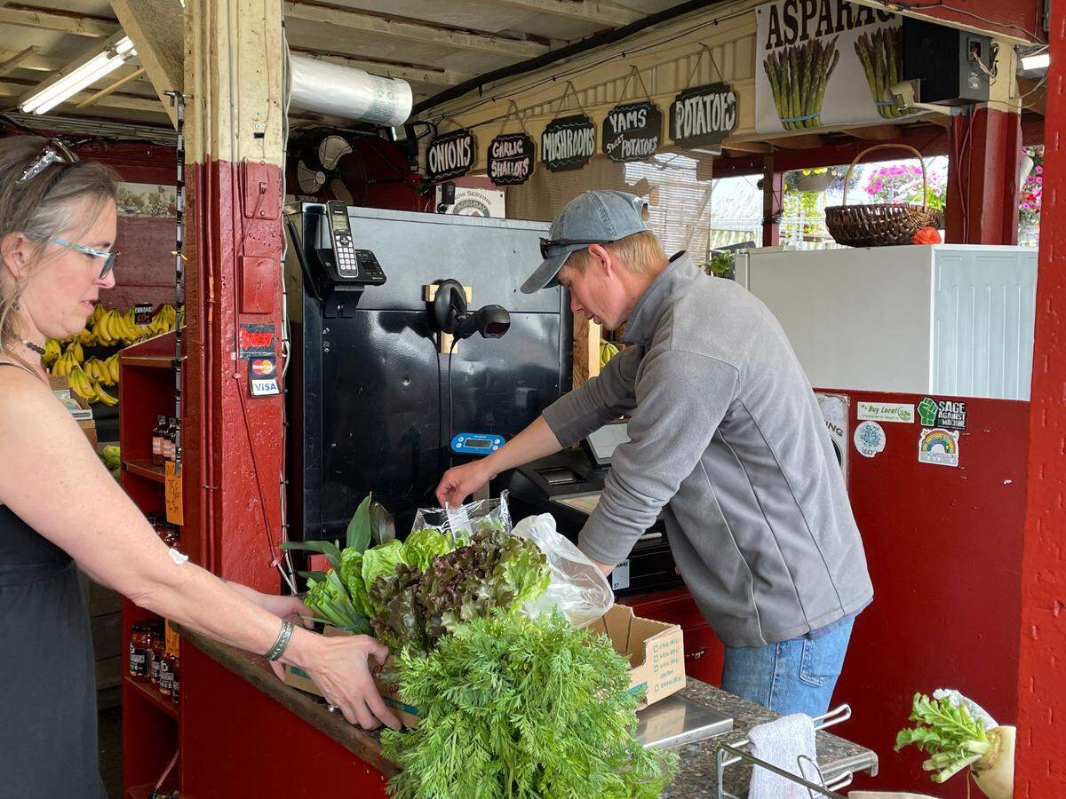 Tristan Chartier, right, rings up a customer at Youngstock’s Nursery & Produce in Bellingham on Tuesday, June 21. His parents are closing the business at the end of June, although Tristan and other family members plan to do some pop-up sales at the James Street location, including Christmas trees.