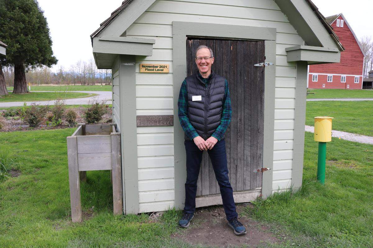 Vic Knox with the Master Gardener Foundation of Whatcom County stands next to a sign on Wednesday, April 6, at Hovander Homestead Park in Ferndale that shows how high floodwaters got in November 2021.