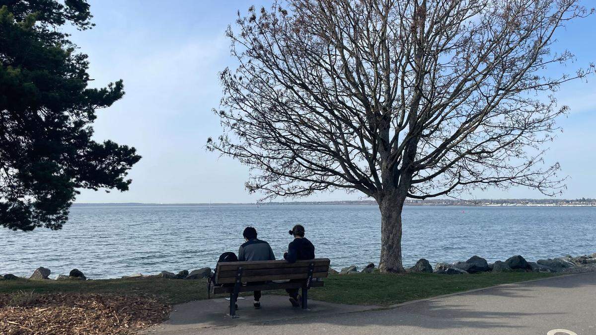 People sit Friday, March 17, 2023, on a bench along the pathway at Boulevard Park on Bayview Drive in Bellingham, Wash.