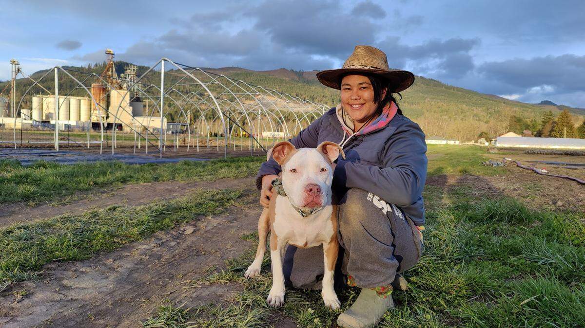 Savannah Flynn sits with her dog on her farm land in Everson, Whatcom County.