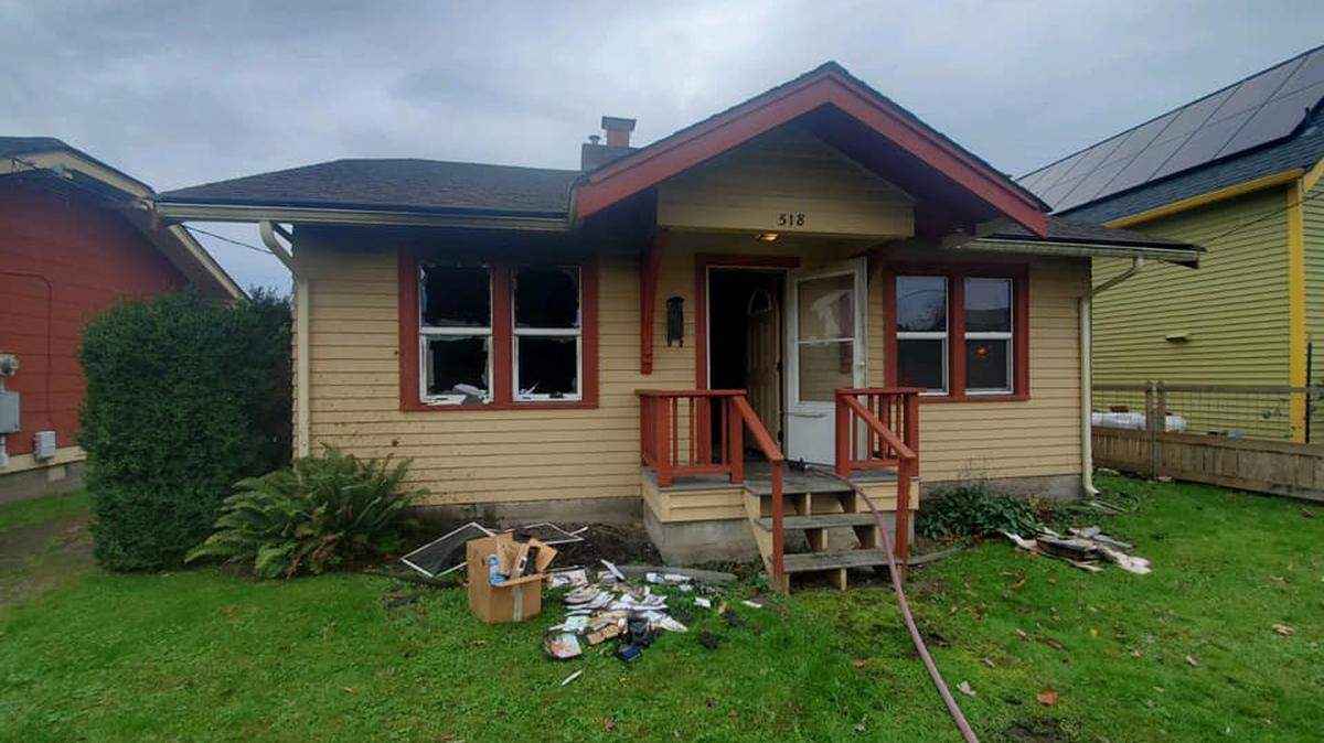 A fire house is stretched through the doorway of a home at 518 E. North St. in the Sunnyland neighborhood of Bellingham, Wash., on Monday, Nov. 1, 2021. Firefighters found an injured woman in the front yard and quickly extinguished the smoky fire inside.