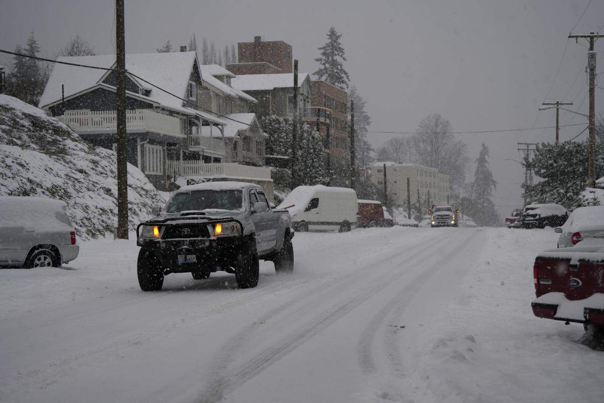 Vehicles drive through snow along N State Street on January 17, 2024, in Bellingham, Wash.