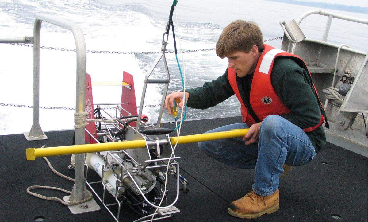 Oregon State University graduate student Anthony Kirincich prepares to launch a monitoring device off the deck of the research vessel, Elakha, in 2004, to gather data about the return of a “dead zone” off the central Oregon Coast. Bottom fish and crabs washing up dead on Oregon beaches were being killed by a recurring “dead zone” of low-oxygen water triggered by global warming, scientists said in 2006. Today, Washington’s coastlines are changing. Excess nutrients and increased water temperatures in the Salish Sea may be the cause of decreased oxygen that can lead to dead zones that kill marine life.