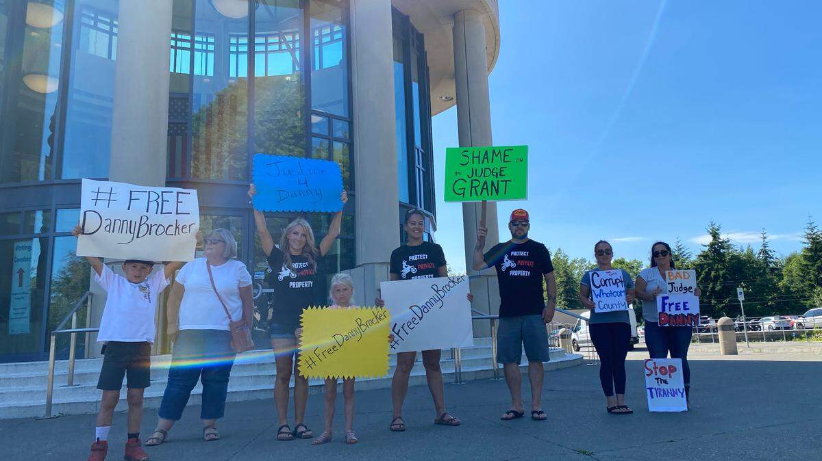 Protesters stand in front of the Whatcom County Courthouse holding signs that read #FreeDannyBrocker on Tuesday, July 21, in Bellingham. Danny Brocker was ordered to jail June 24 for not complying with land use regulations in Whatcom County.