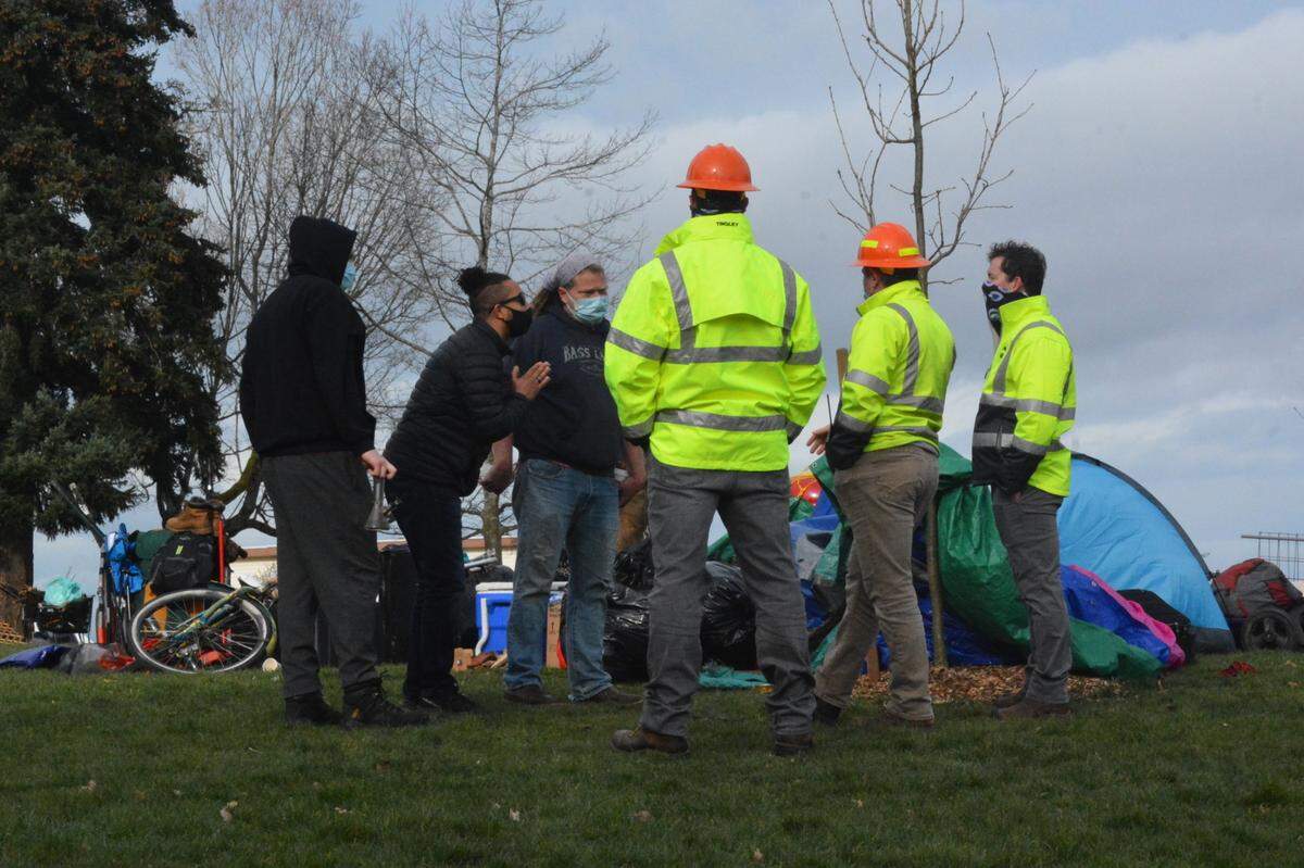 City parks workers talk with protesters angered that the city won’t allow homeless people to camp at Laurel Park in Bellingham Friday, March 19.