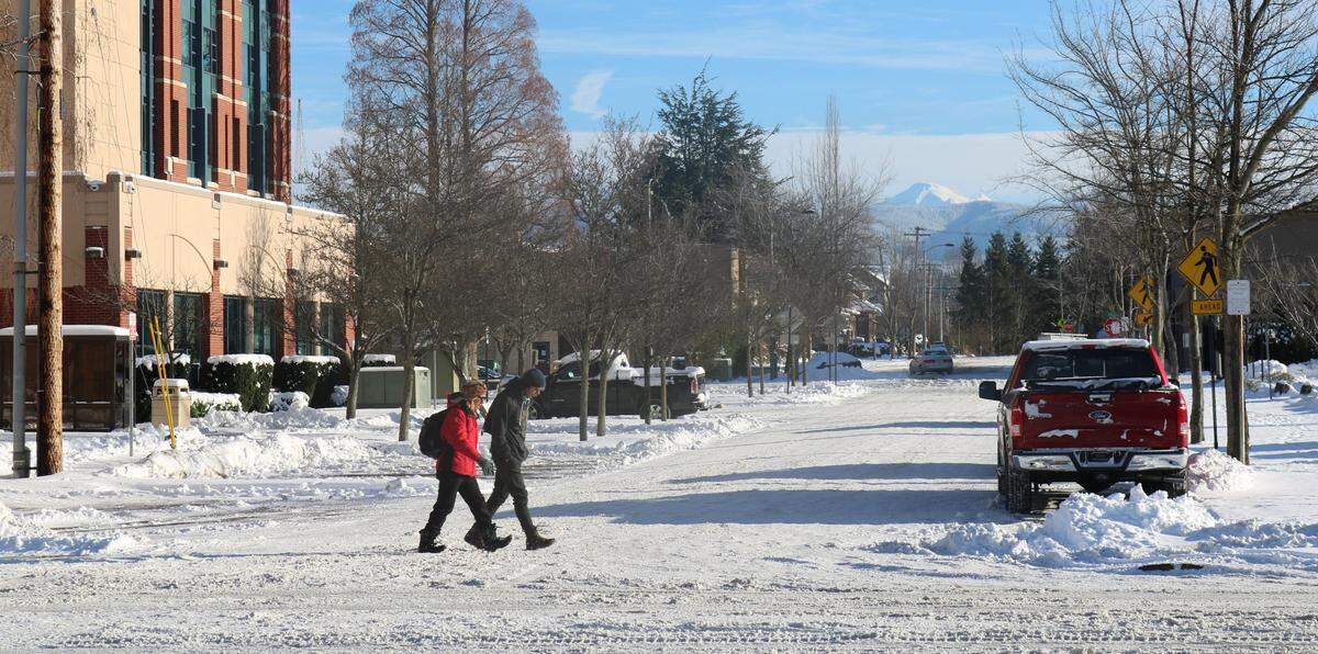 Pedestrians walk on compact snow Monday morning, Dec. 27, at Prospect Street and Central Avenue in downtown Bellingham. The city got a foot or more of snow over the weekend and nearly 2 feet of snow fell over the past two days at Mount Baker.