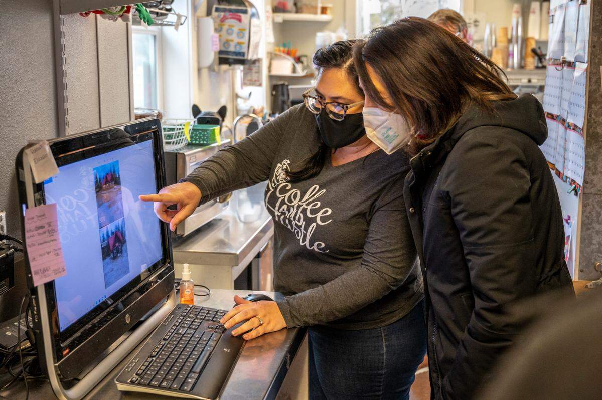 Loca Mocha owner Nicole Postma, left, shows U.S. Sen. Maria Cantwell photos of flood damage to her business on Tuesday, Jan. 25, in Sumas.