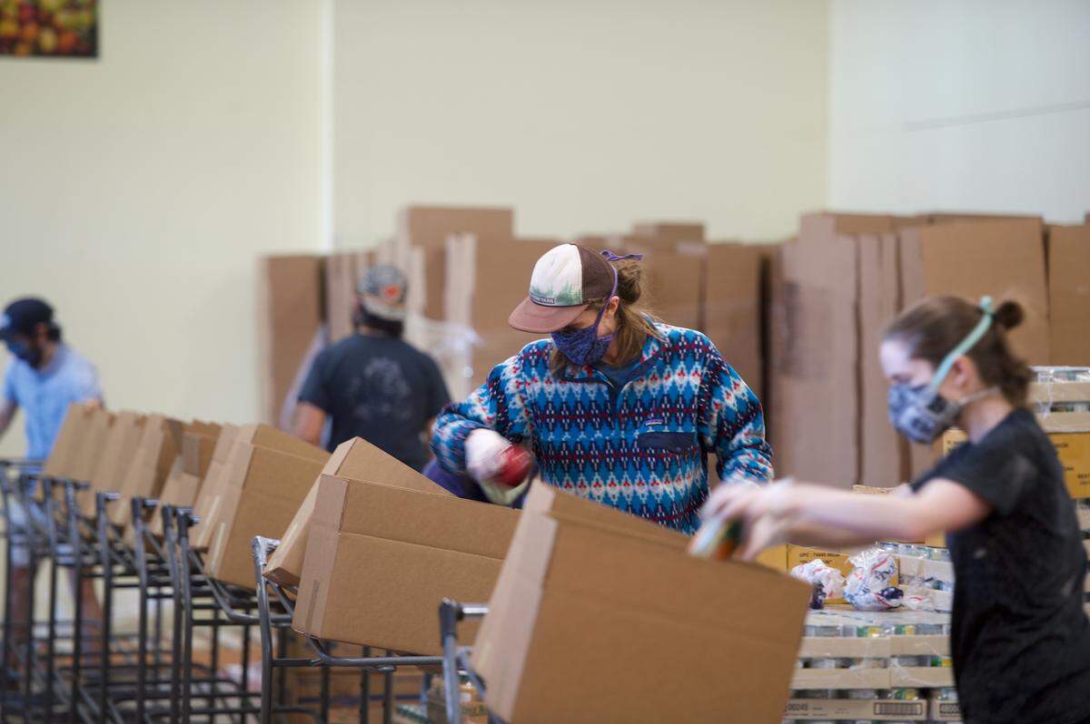 Volunteers package food items at the Bellingham Food Bank on Thursday, April 9, 2020 in Bellingham, Wash.