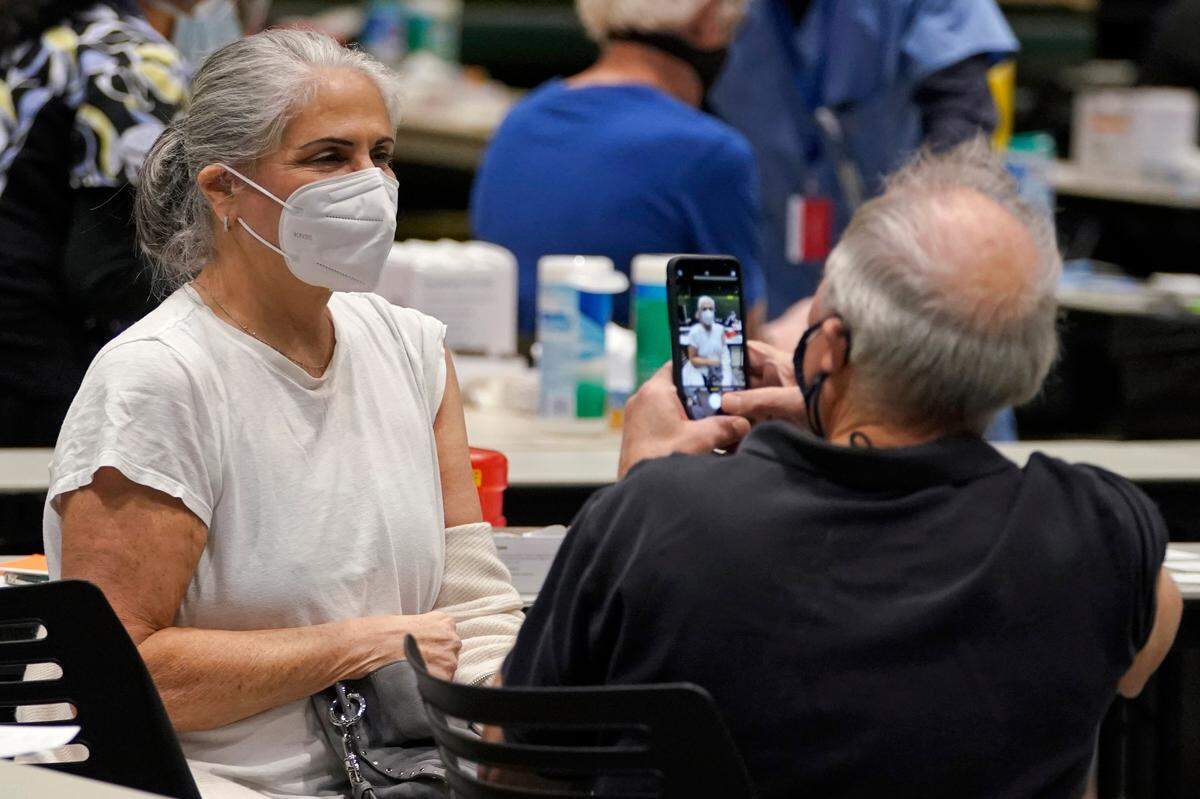 Steve Friedman, right, takes a photo of his wife, Julie Friedman, after they both received the first of two doses of the Pfizer vaccine for COVID-19, Jan. 24 at a vaccination clinic set up in an Amazon.com facility in Seattle and administered Virginia Mason Franciscan Health. COVID-19 vaccine is scarce across Washington state and throughout the United States, but the numbers show it is in particularly short supply in Whatcom County.