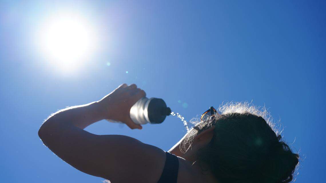 A person drinks water on a hot, sunny day.