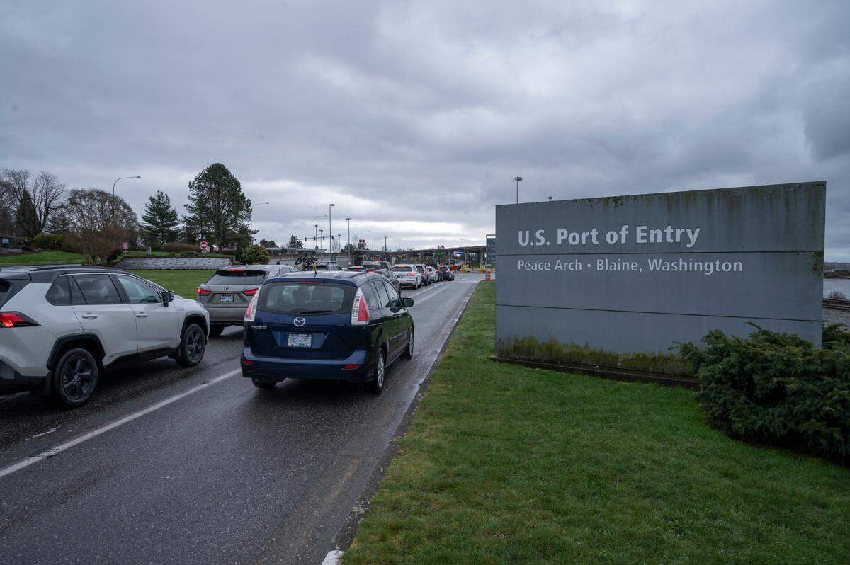 People cross the border between the U.S. and Canada at Peace Arch Park on Friday, March 18, 2022, in Blaine, Wash.