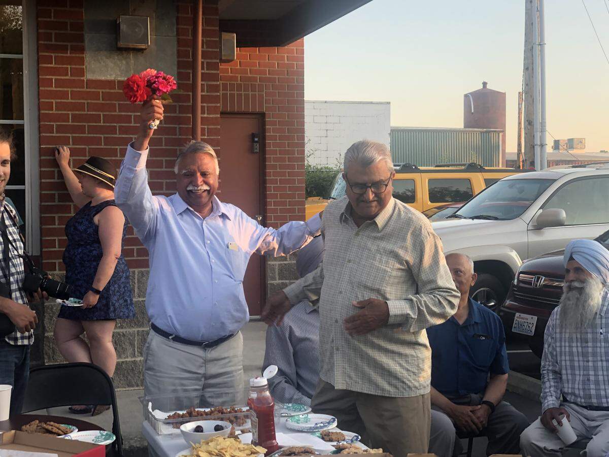 Satpal Sidhu, candidate for Whatcom County Executive, left, holds flowers after his primary victory at the Spice Hut on Aug. 6.