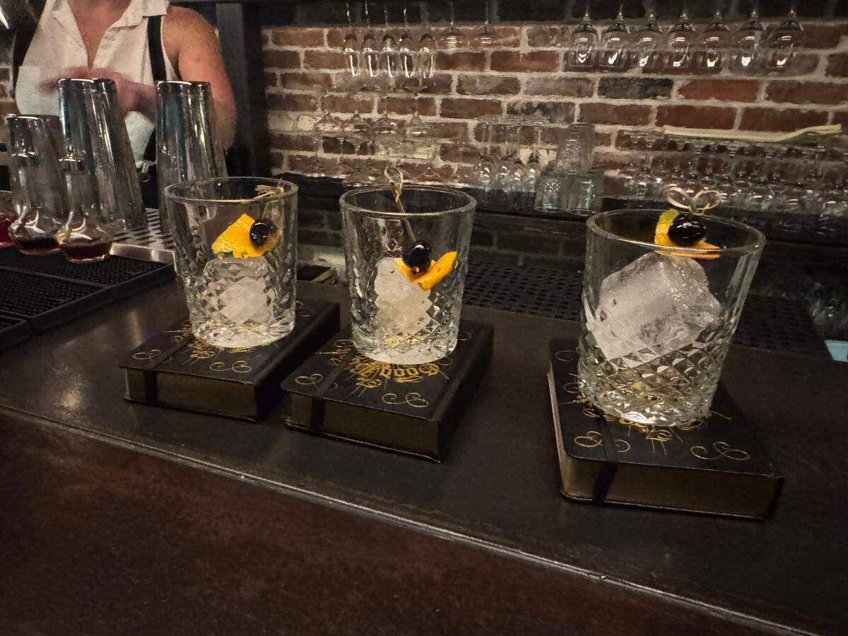 Old Fashioned cocktails served on a replica Bible, hollowed out with a flask inside at The Pastime speakeasy inside Chuckanut Bay Distillery in Bellingham, Wash. on July 21, 2025.
