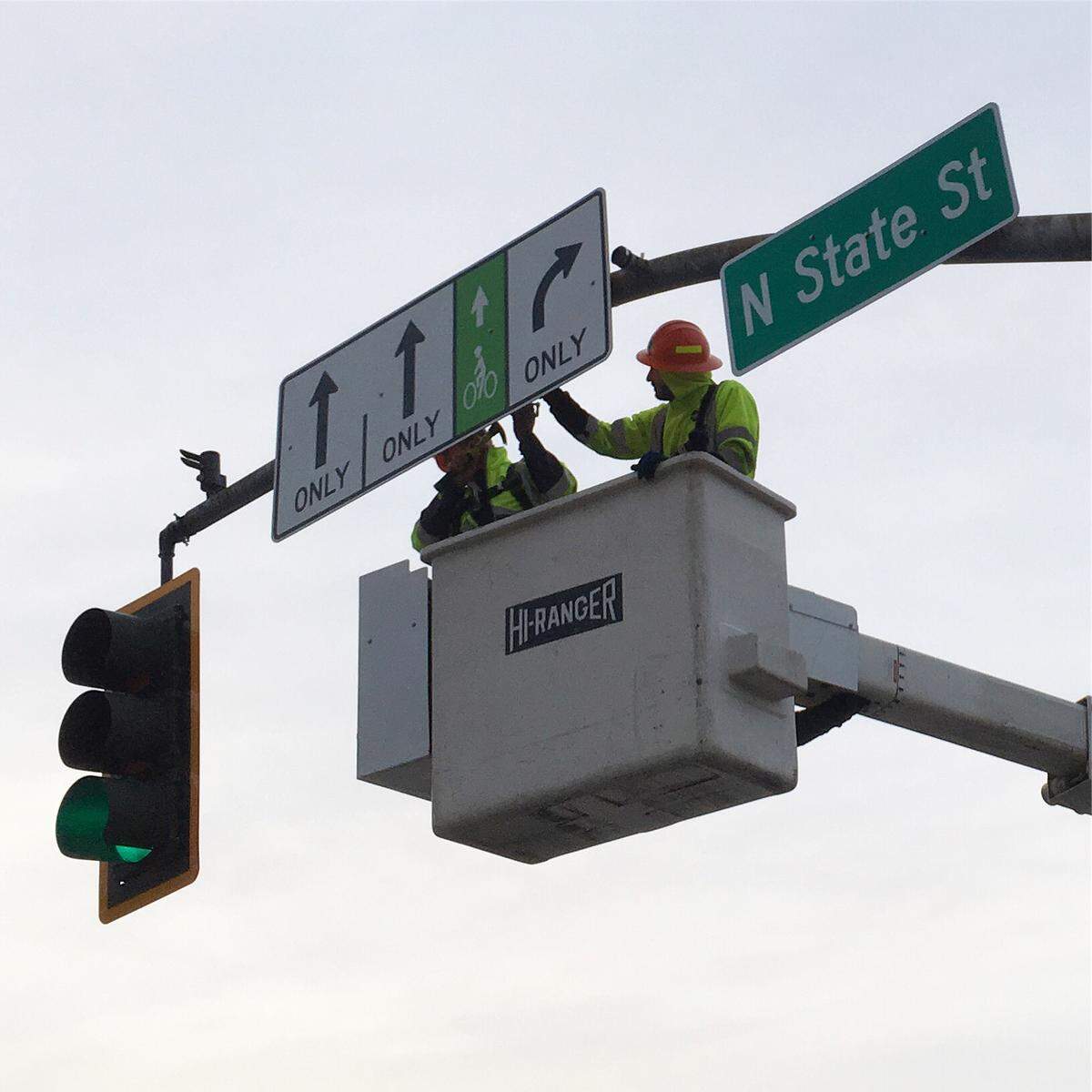 Bellingham city workers install new signs indicating a bike lane was added to eastbound Chestnut Street at the intersection of North State Street in August 2019.